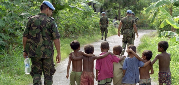 DILI, TIMOR-LESTE - Members of the United Nations Transitional Administration in East Timor (UNTAET) Portuguese contingent are accompanied by a group of local children as they conduct a security patrol. (UN Photo/Eskinder Debebe)